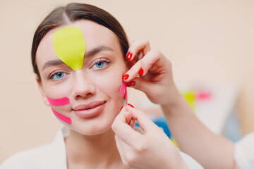 Beautiful woman applying tape lifting treatment on face