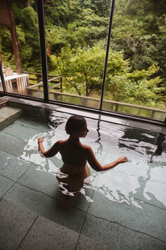 Silhouette of young caucasian woman enjoying.a relaxing thermal waters bath at a traditional Japanese onsen ryokan, view from behind