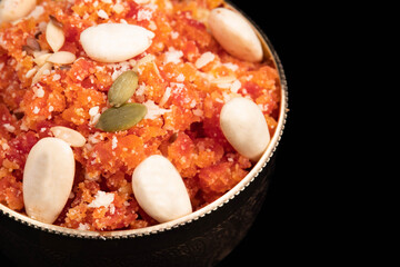 Indian Mithai Gajar Ka Halwa Halva Or Carrot Pudding Halua Made Of Grated Carrots Cream Meetha Mava Sugar Desi Ghee Khoya Mawa And Dry Fruits Badam Kaju Isolated On Black Background With Copy Space