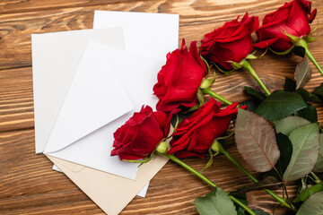High angle view of roses near envelopes and papers on wooden surface