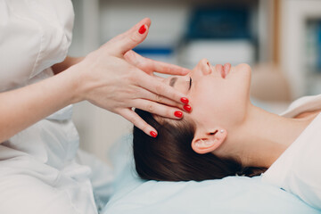 Beautiful young woman getting face treatment massage at beauty spa salon.