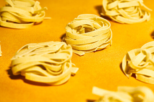 From above set of raw fettuccine pasta nests placed on bright yellow table