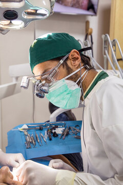 Focused professional dentist examining teeth of patent with dental instruments in bright room room in clinic