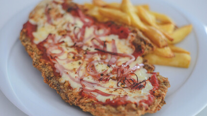 Plato argentino de milanesa napolitana y patatas fritas 