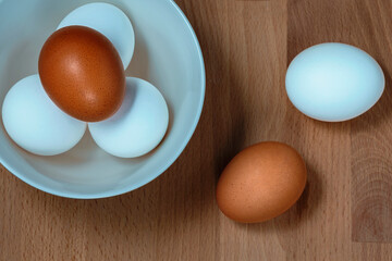 several fresh chicken eggs in a ceramic cup on a wooden background. Healthy eating concept