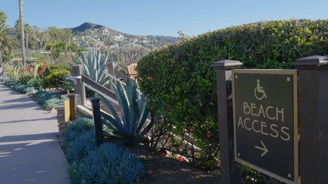 Camera pan of a beach access sign, along a walking path, in Laguna Beach California. Slowed to half speed.