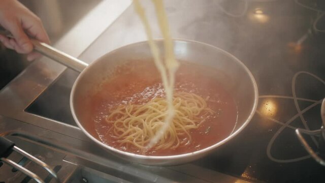 Chef cooking bolognese fresh pasta with tomato sause, man making traditional italian dinner on restaurant kitchen, tasty food, high haute kitchen 