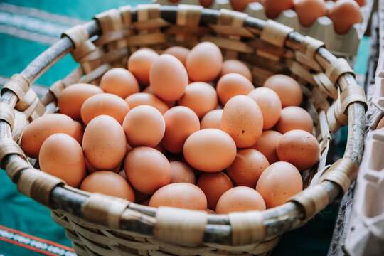 Wicker basket full of brown organic eggs placed on counter on local food market