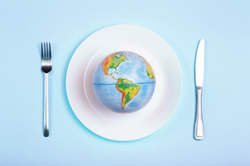 Globe on a plate for food on a blue background. Power, economy, politics, globalism, hunger,...