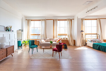 Vintage studio apartment interior in light colors in old style. huge room with large windows with a living room area and a bedroom area. direct sunlight inside.