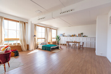 Vintage studio apartment interior in light colors in old style. huge room with large windows with a living room area and a bedroom area. direct sunlight inside.