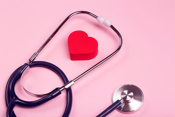 World heart day background. Heart as a symbol of health, treatment, charity, donation and cardiology on a pink background with a medical statoscope.