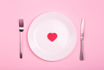 Heart on an empty plate on a pink background. Minimal art creative concept. Red heart as a symbol of love, romance and 