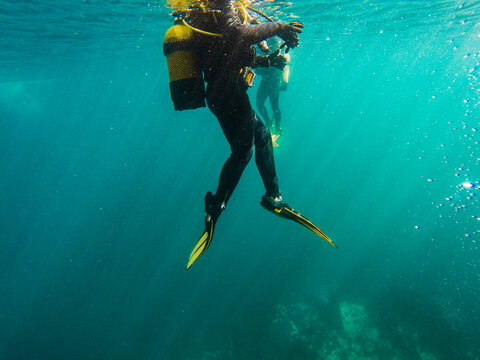 Cropped unrecognizable divers scuba diving in deep ocean