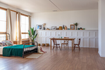 Vintage studio apartment interior in light colors in old style. huge room with large windows with a living room area and a bedroom area. direct sunlight inside.