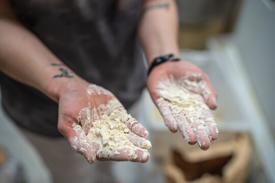 Unrecognizable crop cook showing hands with raw dough while standing in kitchen of bakehouse