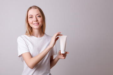 Attractive young girl holding a bottle of cosmetics on a white background