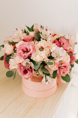Bouquet with pink anemones and roses and eucalyptus branches in round pink box. Satin ribbon on the box. Present, spring time, happy women's day