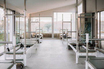 Bright interior of gym with contemporary pilates reformers placed in spacious facility for workouts