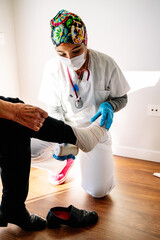 young girl nurse bandaging lady with sprained foot