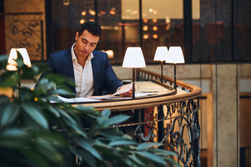 Serene young male entrepreneur leaning over a pile of papers