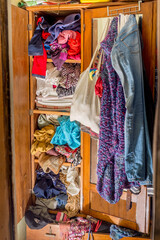 Closet clogged with clothes and textiles. Second hand reuse. Decluttering and cleaning the cabinet