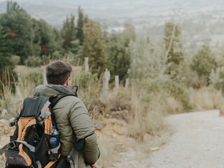 Fototapeta premium joven joven de espaldas esta caminando dentro del bosque por un pequeño sendero con una maleta de viajes