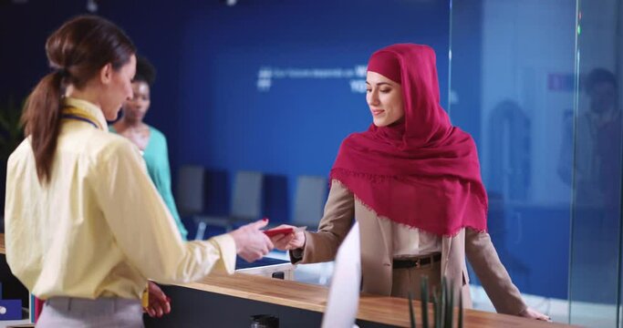 Female security agent woman standing by registration counter checking passenger passport and visa information using pc computer. Check-in airport.