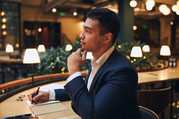Pensive man with a ball-point pen staring into the distance