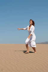 woman dressed in white enjoying in the sand dunes on the sunny day