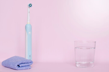 the electric brush is on the table next to the glass.oral hygiene