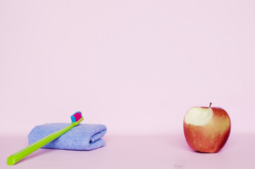 there is a brush and a towel on the table. there is an apple nearby.oral hygiene