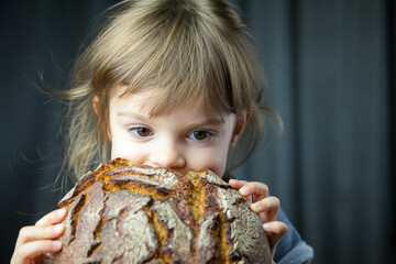 little girl eating a big circle rye bread