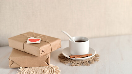 background with gift boxes wrapped in craft paper and decorated with a paper heart. cup of tea