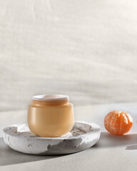 Beauty lifestyle background with Opened Jar of face cream and fresh tangerines.  winter skin care concept