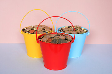A Red, Yellow And Blue Bucket Full Of Cash. Money Savings Concept. © dean
