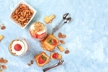 Fototapeta na wymiar Strawberry yogurt with berries, crackers and muesli on a bright table, fruit salad. Healthy breakfast with ingredients, natural food concept, lifestyle, food for children, selective focus, top view,