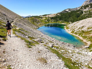 Fototapeta na wymiar Female hiker hiking along crystal clear mountain lake.