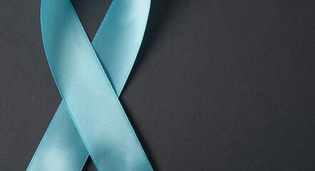 Blue crop ribbon for cancer awareness on gray desk with copy space