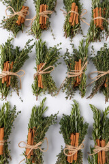 Fototapeta na wymiar Bundles with herbs tied to cinnamon sticks, spices for mulled wine on white background