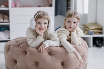 Girls sisters lie in a modern dressing room and look at the camera