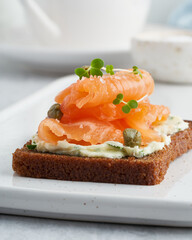 Smorrebrod - traditional Danish sandwiches. Black rye bread with salmon, cream cheese, capers on white background. Vertical, macro, close up