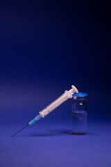 Vaccine bottle phial with no label, medical syringe injection needle. isolated on blue background....