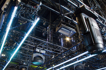 Moving heads spotlight devices are clamped on a rigging steel truss. Installation of professional...