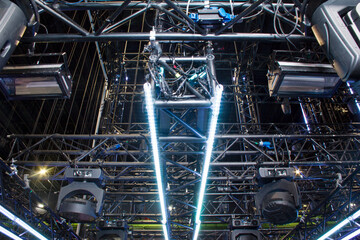 Black aluminum steel trusses with led bars lighting and moving heads spotlight devices. Installation of professional concert equipment for a tv show.