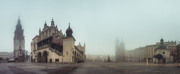 Krakow, Poland, main square panorama with Cloth Hall and St Mary's church on foggy November morning