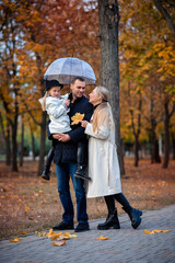 Happy family on a walk in the park under an umbrella