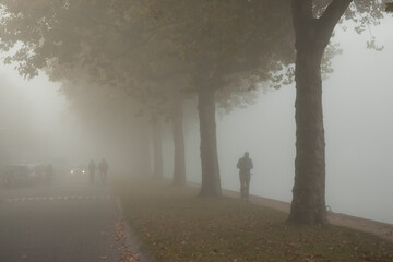 People cycling or waking outdoors during a very foggy, misty day