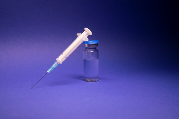 Vaccine bottle phial with no label, medical syringe injection needle. isolated on blue background....