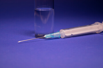 Vaccine bottle phial with no label, medical syringe injection needle. isolated on blue background. Development of coronavirus vaccine COVID-19. cure. World race in researching